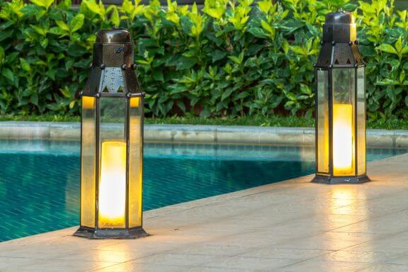 To lanterner ved poolens kant.