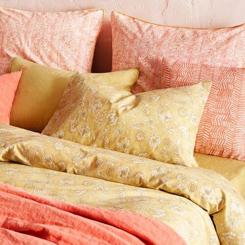 Sengetøj i gule og orange nuancer.