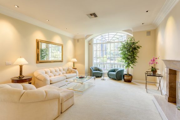 Creme stue med stort vindue og spejl på væggen.