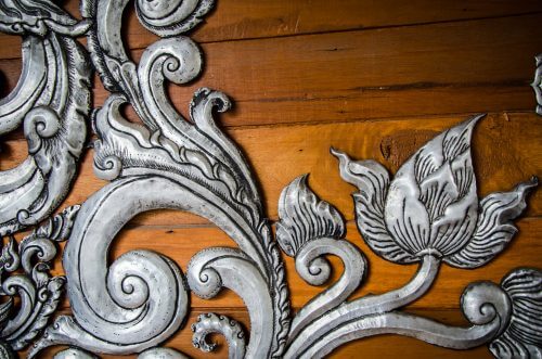 Dekoration i sølv på træmøbel.